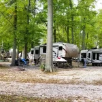 RV campers enjoying a shaded campsite at Woods-N-Waters Kampground in Columbus, Indiana