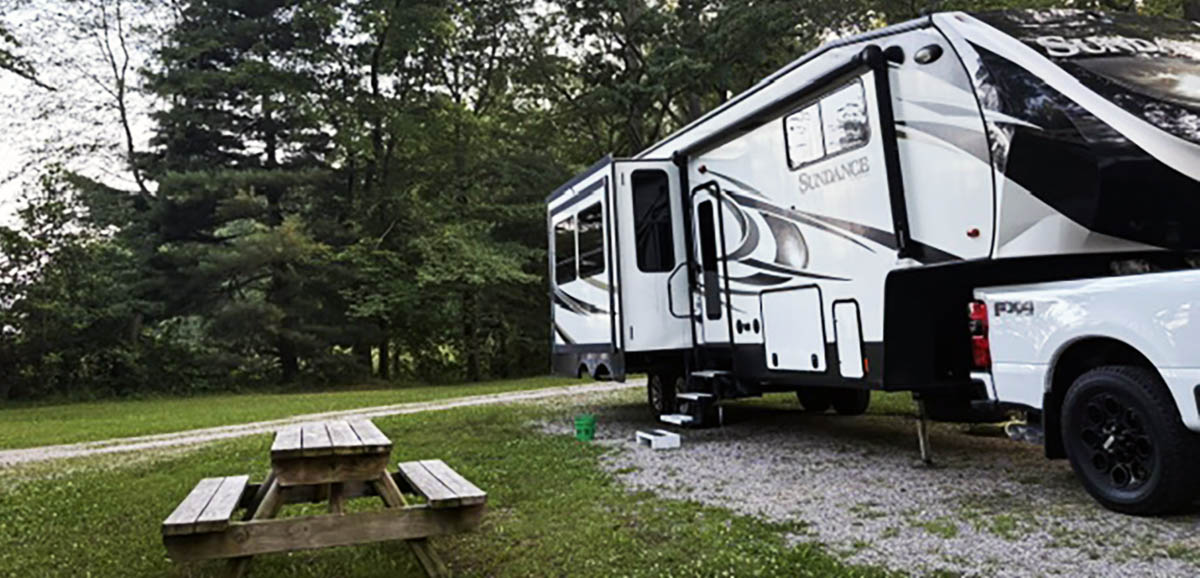 RV campsite surrounded by mature trees at Woods-N-Waters Kampground near Columbus, Indiana.