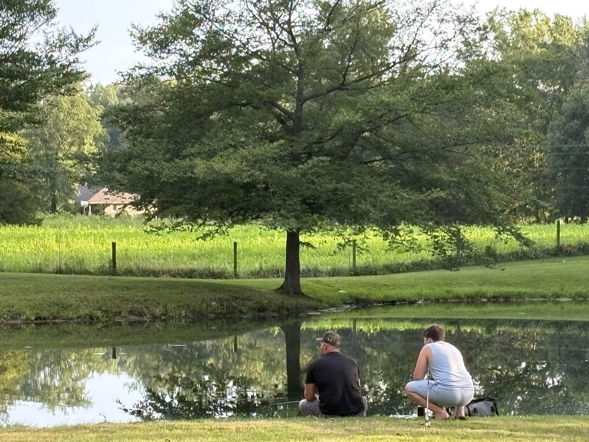 Campers fishing beside the pond at Woods-N-Waters Campground in Columbus, Indiana